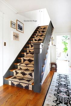 a stair case with rugs on the bottom and handrail