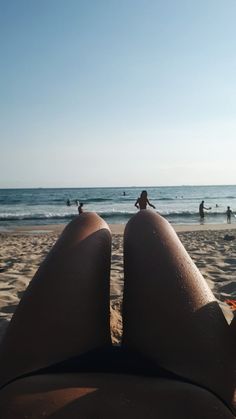 someone is laying down on the beach with their feet in the sand looking at the ocean