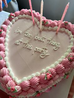 a heart shaped cake with pink frosting and candles