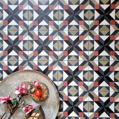 a table with flowers on it in front of a patterned wall