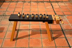 a wooden table with six pegs sitting on it's legs in front of a brick floor