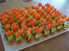 carrots and cucumbers are arranged on a white platter with toothpicks