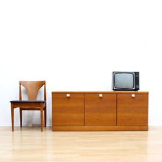 a chair and television set sitting on top of a wooden dresser next to each other