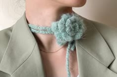 a woman wearing a green jacket with a crocheted flower on it's neck