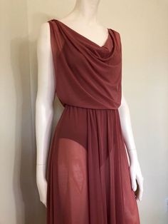 a mannequin wearing a red dress with one side slited and an asymmetrical neckline