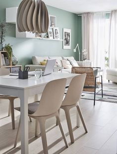 a dining room table with chairs and a laptop computer on it, in front of a couch