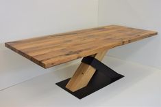 a wooden table sitting on top of a black metal base