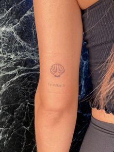 a woman with a shell tattoo on her arm