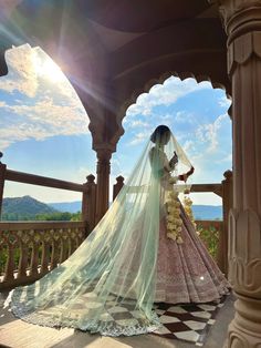 a woman in a wedding dress standing on a balcony with her veil draped over her head