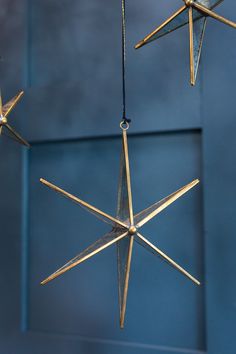 three gold stars hanging from strings in front of a blue wall