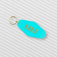 a blue keychain with the word kill on it sitting on a white surface