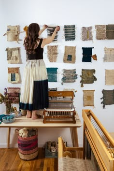 a woman standing on top of a wooden table in front of many pieces of cloth