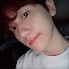 a young boy with red hair and blue eyes is looking at the camera while wearing a white t - shirt