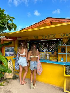 two girls standing in front of a yellow shack