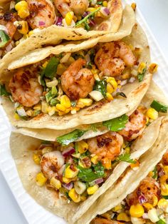 shrimp tacos with corn and cilantro on a white plate