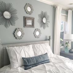 a bed with white sheets and pillows in front of mirrors on the wall above it