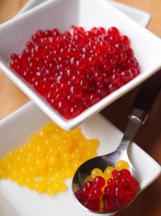 two bowls filled with gummy bears next to a spoon full of jellybeans