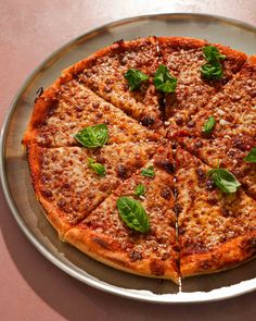 the pizza is cut into four pieces and has basil leaves on it, along with other toppings