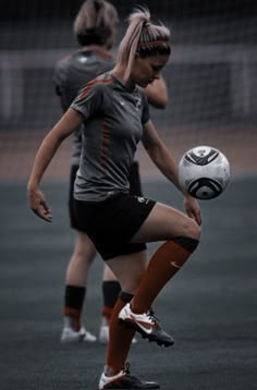 two girls playing soccer on a field with the ball in front of their head and one girl wearing an orange skirt