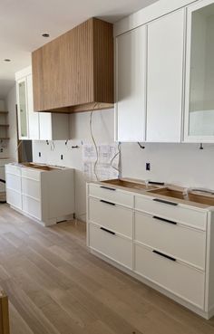 an empty kitchen with white cabinets and wood floors