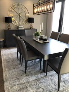 a dining room table and chairs with a clock on the wall in the back ground