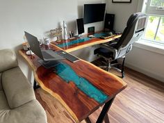 a laptop computer sitting on top of a wooden desk next to a couch in a living room