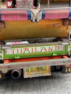 a colorful truck parked in front of a building with the word thailand painted on it's side