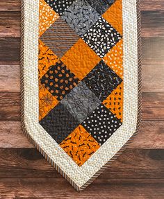 an orange and black patchwork tie hanging on a wooden wall with wood planks