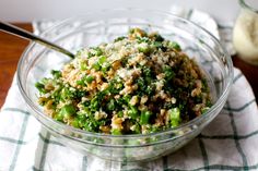 a glass bowl filled with broccoli and other food on top of a table