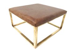 a brown leather ottoman with gold metal frame and square foot rest on an isolated white background