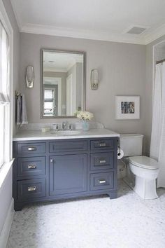 an image of a bathroom with blue cabinets and white fixtures on the counter top in front of a mirror