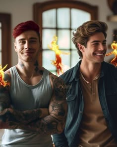 two men with tattoos standing next to each other and smiling at the camera while holding fireballs in their hands