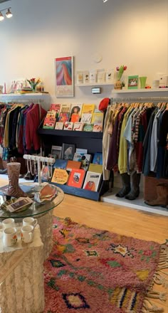 a clothing store filled with lots of different types of shirts and hats on display in front of a glass table