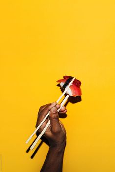 a hand holding two lollipops with the flag of egypt on them against a yellow background