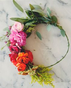 flowers arranged in the shape of a circle on a marble surface with greenery and leaves