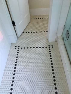 a bathroom floor with black and white hexagonal tiles on the bottom half of it