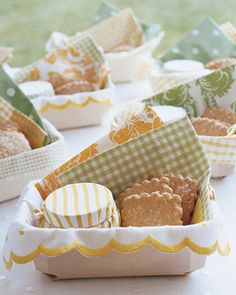 small boxes filled with cookies sitting on top of a white table covered in green and yellow gingham paper