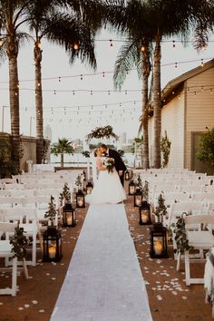 a bride and groom kissing at the end of their wedding ceremony in front of palm trees