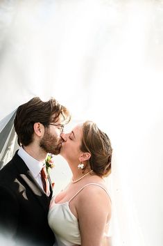 a bride and groom kissing in front of the sun