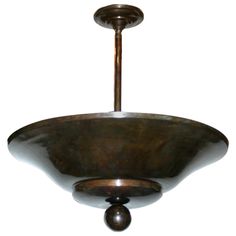 a metal bowl hanging from the ceiling with a light fixture on one side and an object in the middle