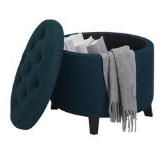 a blue ottoman with a blanket on it and some folded items in the bottom compartment