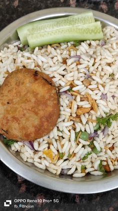 a plate with rice, meat and cucumbers in it on a marble table