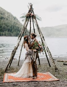 a man and woman standing in front of a teepee