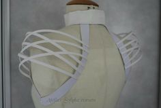 a mannequin's back with white ribbon wrapped around the neck and sides