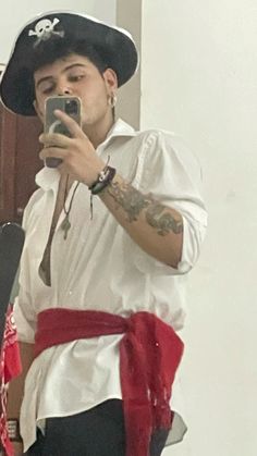 a man in a pirate costume taking a selfie with his cell phone while wearing a hat