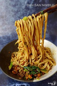 the book cover shows chopsticks holding noodles with meat and vegetables in it, on top of a black plate