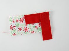 a piece of fabric with red and green flowers on it next to a pair of scissors