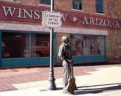 a statue is standing on the sidewalk in front of a building with a street sign