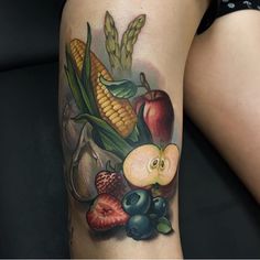 a woman's leg with an apple and corn on the cob tattoo