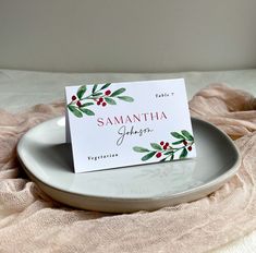 a white plate topped with a card on top of a table next to a pink blanket